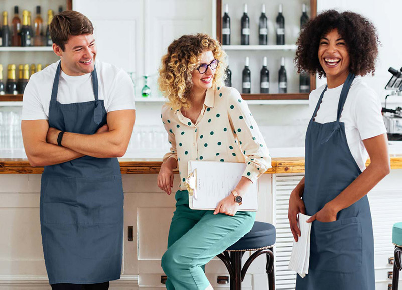 Clients of Integrated Tax Services smiling and standing in aprons at their wine bar cafe