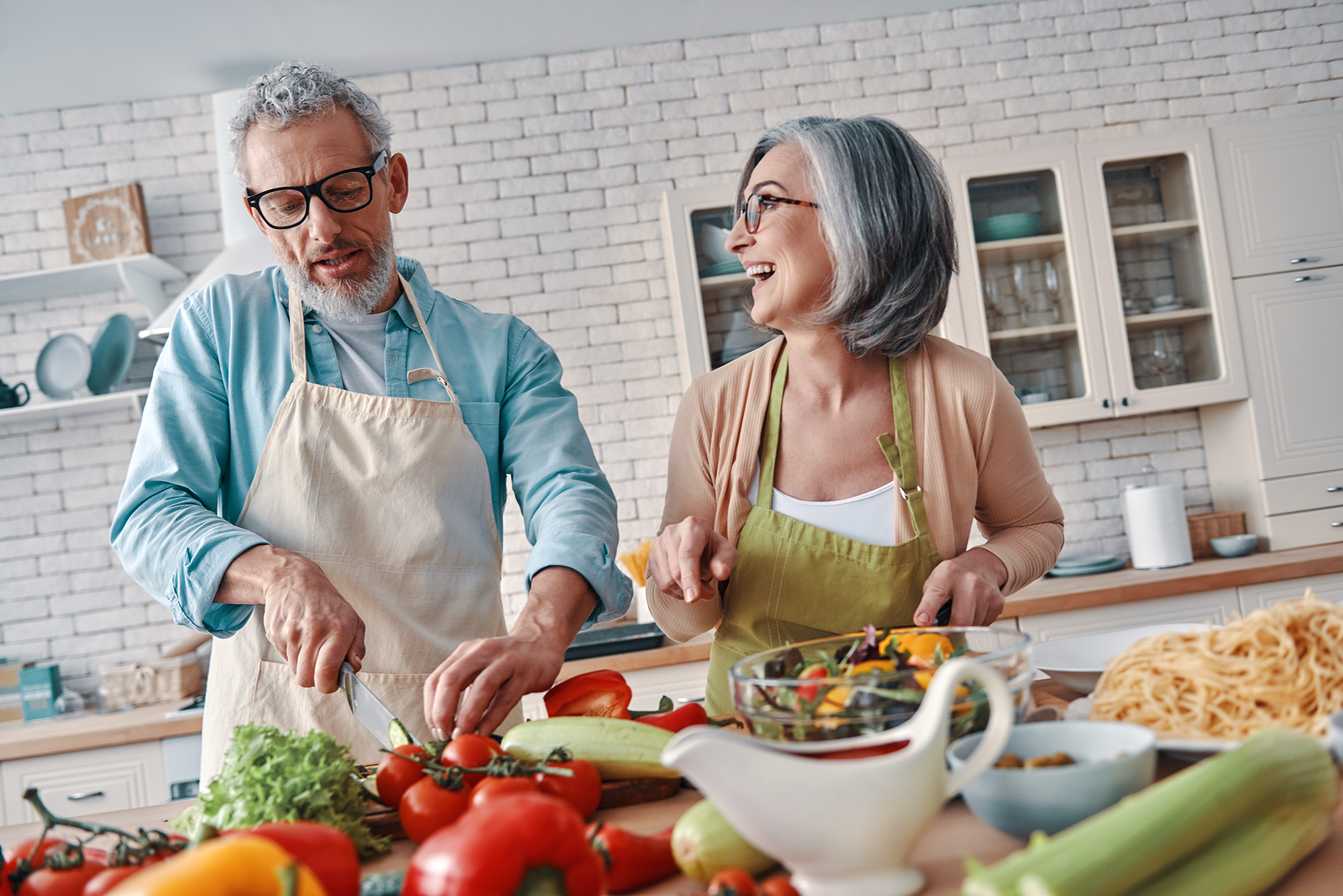 a couple smiling while cooking in the kitchen