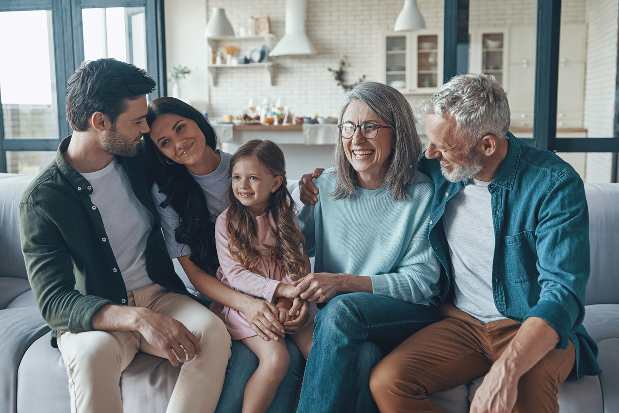 three generations of family smiling on the couch